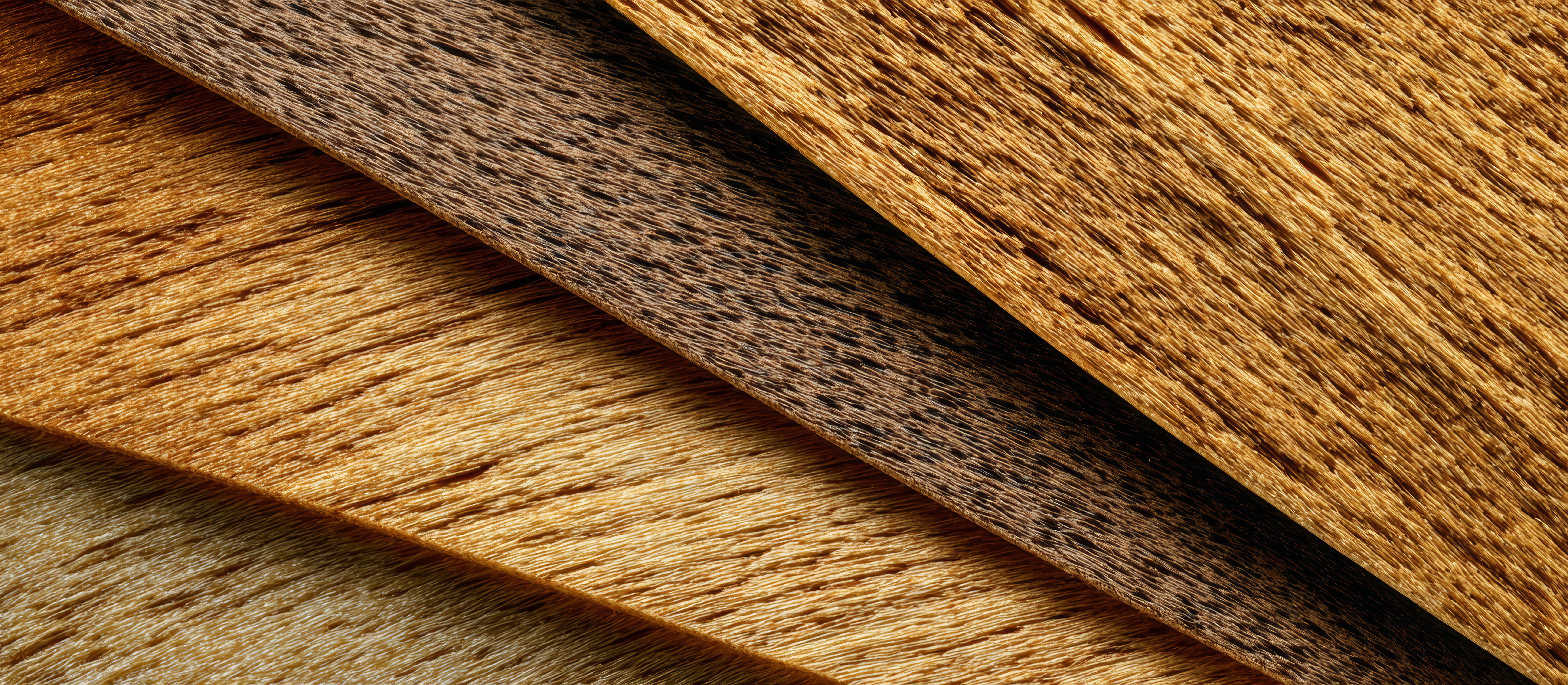 Diagonal wooden planks displaying rich warm tones, highlighting natural wood grain and textural depth Warm-toned wooden planks are arranged diagonally, creating a visually appealing pattern that showcases the natural grain and texture of the wood