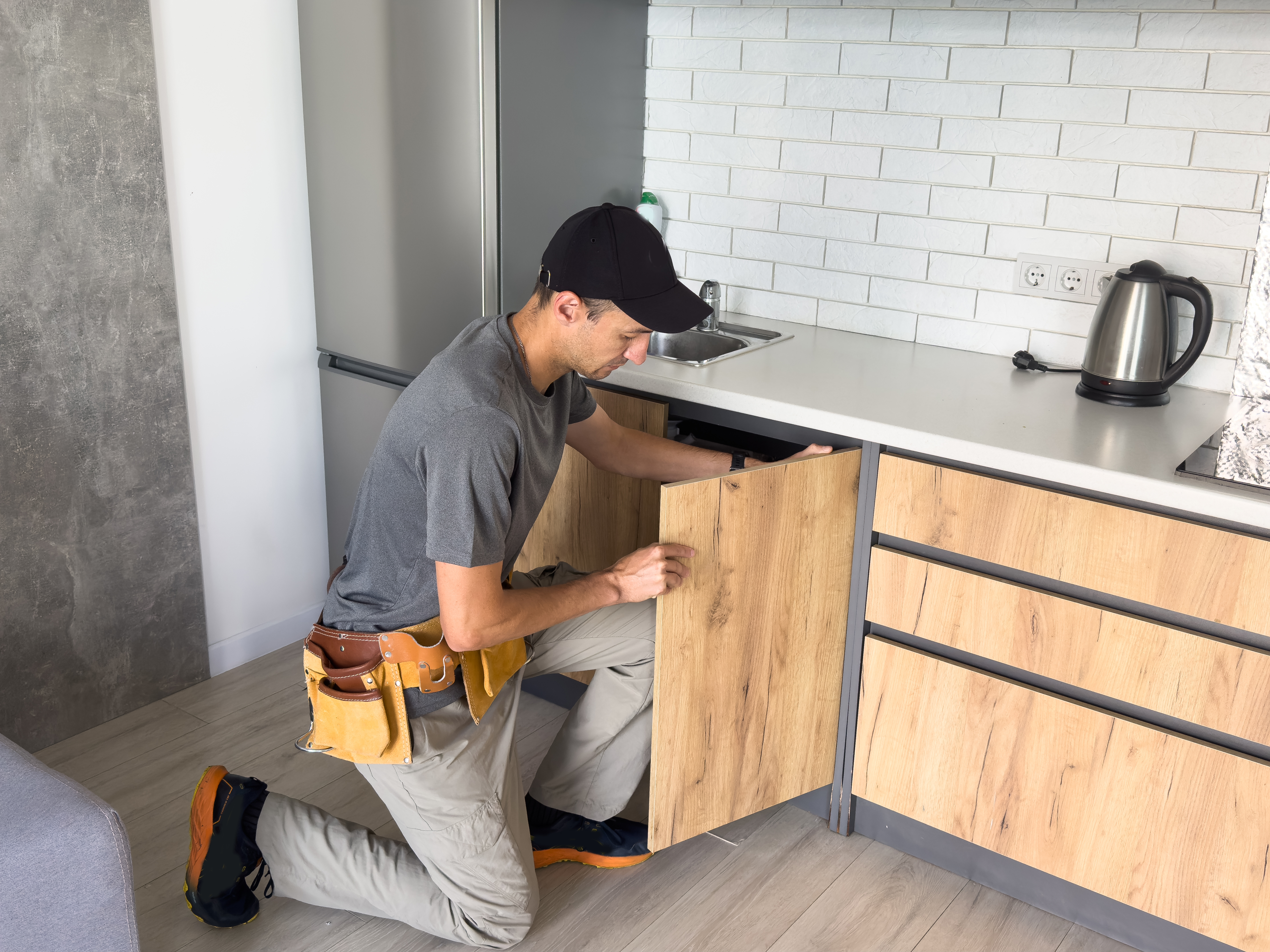 The carpenter finalizing the assembly of the kitchen shelf on the wall. High quality photo